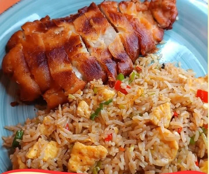 Gebackene Hühnchenbrust serviert mit gebratenem Reis in einem eleganten Teller.