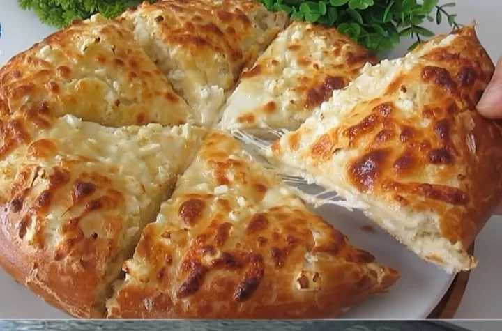 Griechisches Käsebrot mit frischem Feta und Oliven, serviert auf einem Holzbrett.