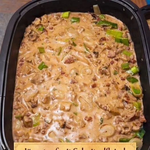 Jägertopf Gericht mit Pilzen, Fleisch und frischen Kräutern auf einem Teller serviert.