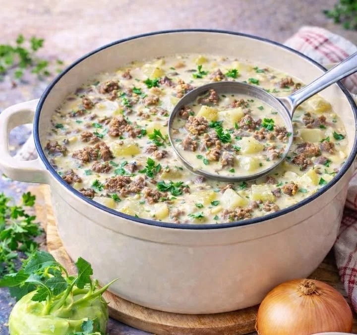 Schüssel mit leckerer Kohlrabi Hacksuppe, serviert mit frischen Kräutern.