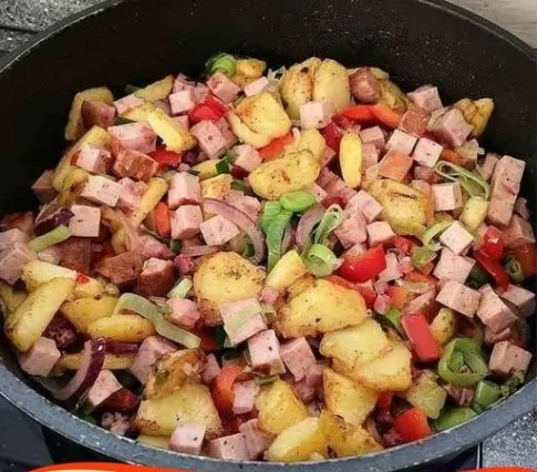 Leberkäse-Pfanne serviert mit Beilagen auf einem Teller