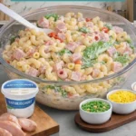 Nudelsalat mit Joghurtsauce auf einem Teller, dekoriert mit frischen Kräutern.