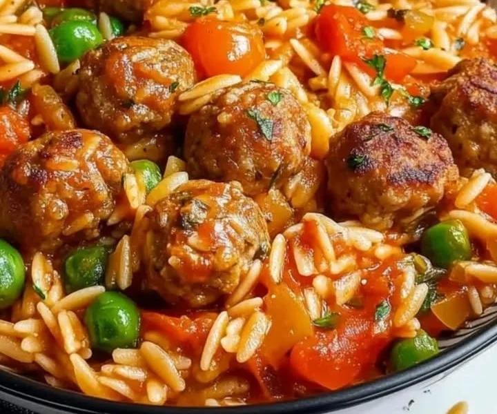 Orzo-Pfanne mit Hackbällchen und frischem Gemüse auf einem Teller serviert.