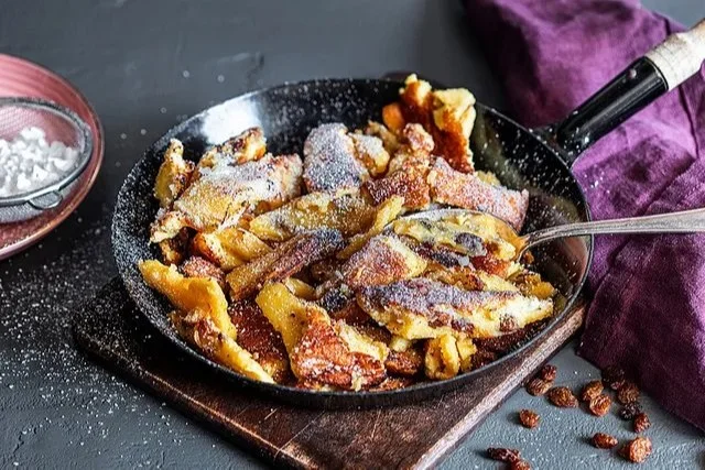 Fluffiger Kaiserschmarrn von Altbaerlis, serviert mit Puderzucker und Apfelmus.