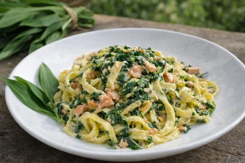 Bärlauch-Tagliatelle mit Räucherlachs und cremiger Sauce auf einem Teller