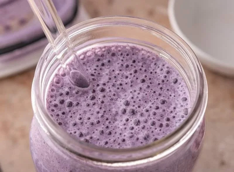 Leckerer Blaubeerproteinshake in einem Glas mit frischen Blaubeeren