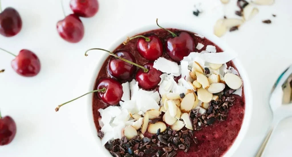 Dunkle Kirsch-Smoothie in einer Schüssel mit frischen Zutaten