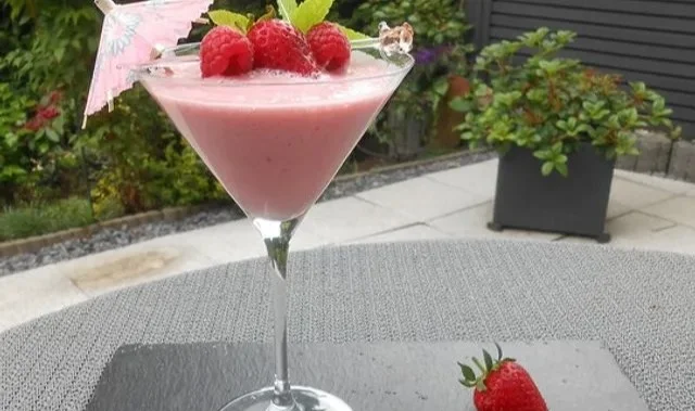 Erdbeer-Himbeer-Smoothie in einem Glas mit frischen Früchten dekoriert
