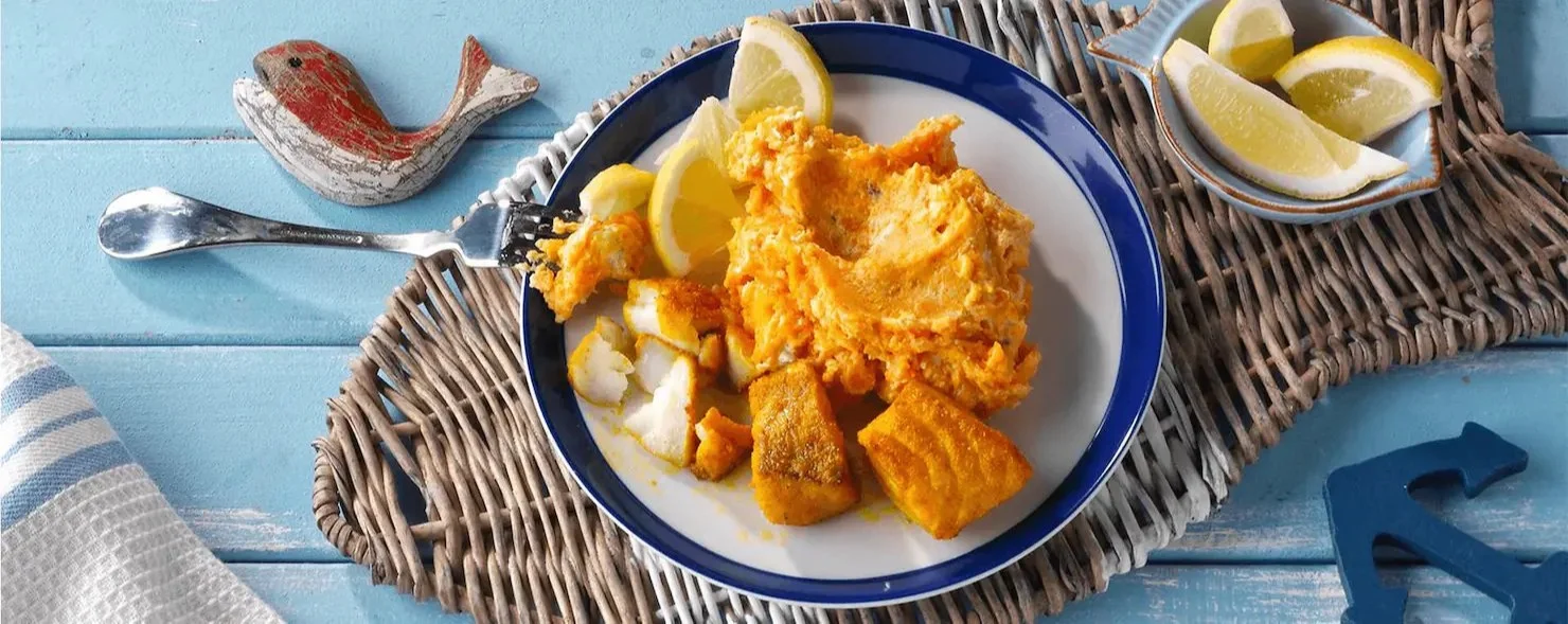 Knusprig gebratener Fisch mit Süßkartoffelpüree auf einem Teller serviert