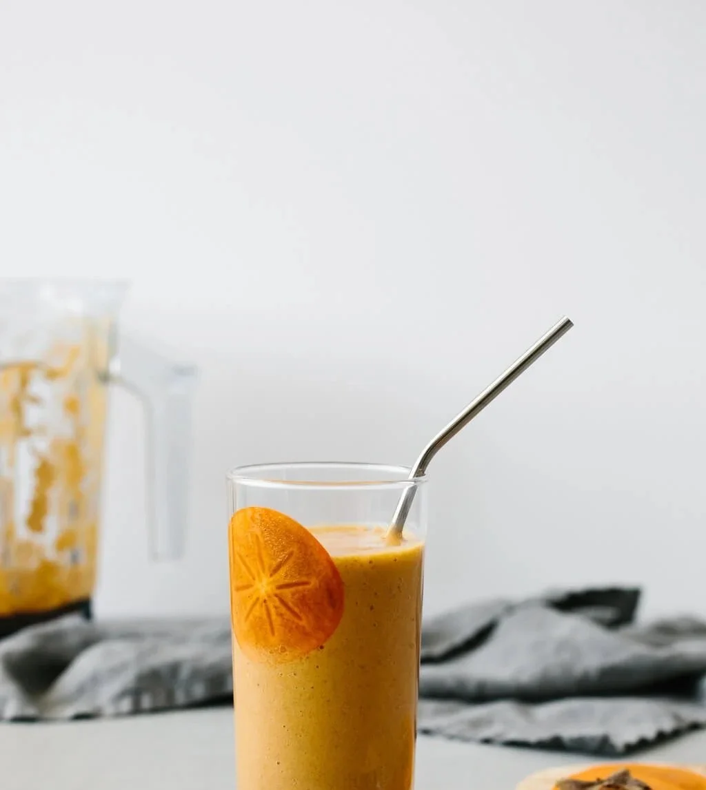 Gewürzter Persimone-Smoothie in einem Glas mit frischen Zutaten