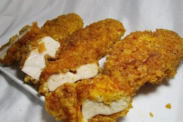 Hähnchenbrust in knuspriger Cornflake-Kruste auf einem Teller