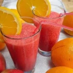 Erfrischender Himbeer-Orange-Apfel-Smoothie in einem Glas mit frischen Früchten