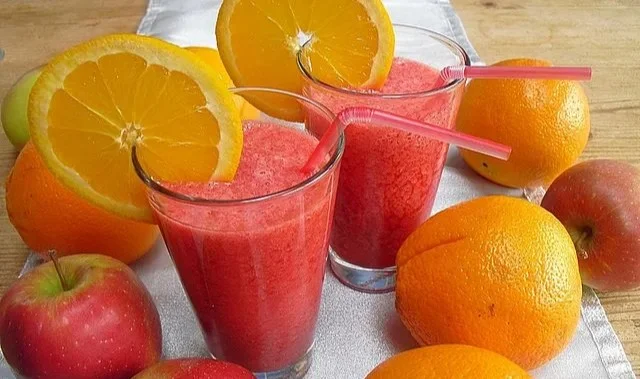 Erfrischender Himbeer-Orange-Apfel-Smoothie in einem Glas mit frischen Früchten