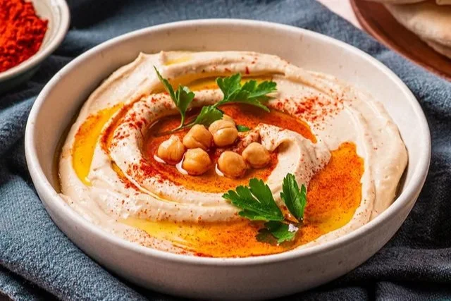 Hummus mit Tahini auf einem Teller, serviert mit frischem Brot und Gemüse