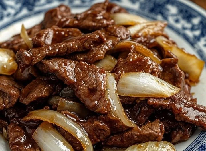 Karamellisiertes Rindfleisch mit Zwiebeln auf einem Teller serviert.