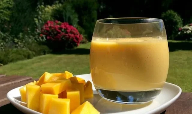 Leckerer Mango-Bananen-Smoothie in einem Glas mit frischen Früchten