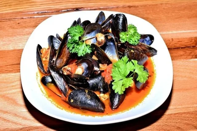 Muscheln in würziger Tomate-Weißwein-Sauce an einem Teller serviert