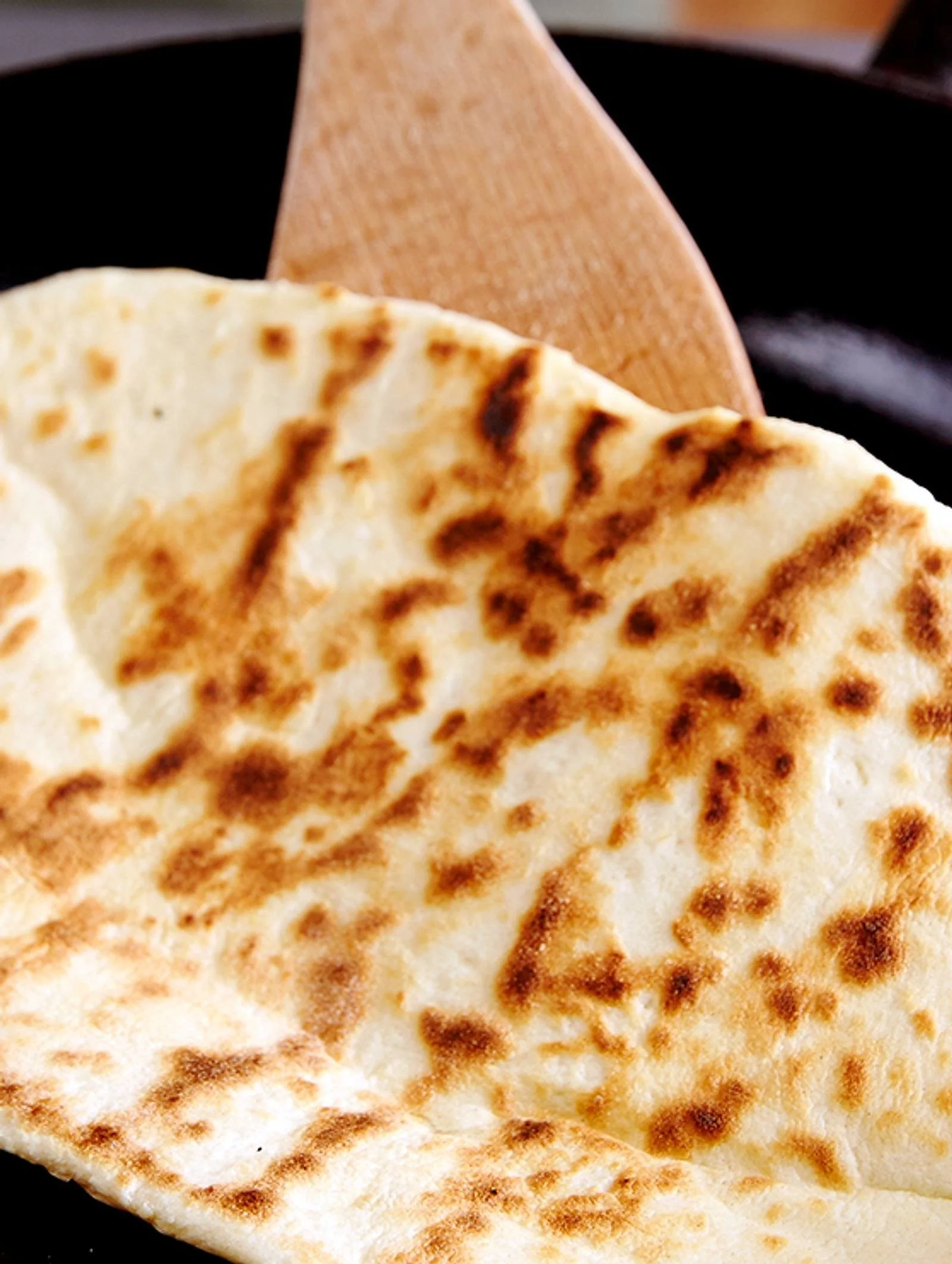 Frisches Naan-Brot nach indischem Rezept, serviert mit Gewürzen und Kräutern