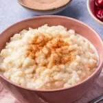 Perfekter Milchreis nach Grundrezept, serviert in einer Schüssel mit Zimt und Zucker