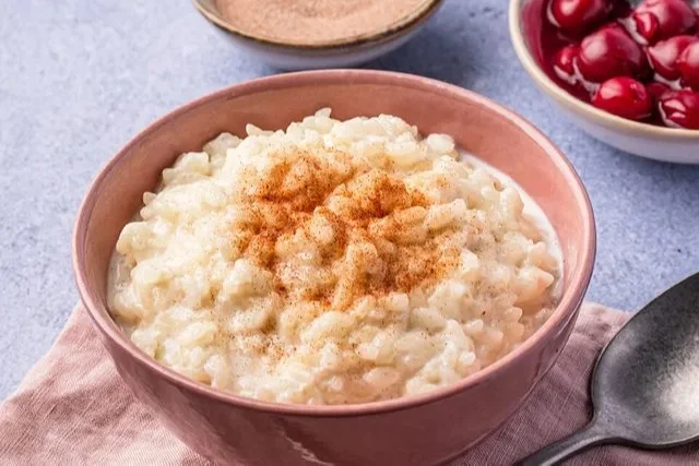 Perfekter Milchreis nach Grundrezept, serviert in einer Schüssel mit Zimt und Zucker