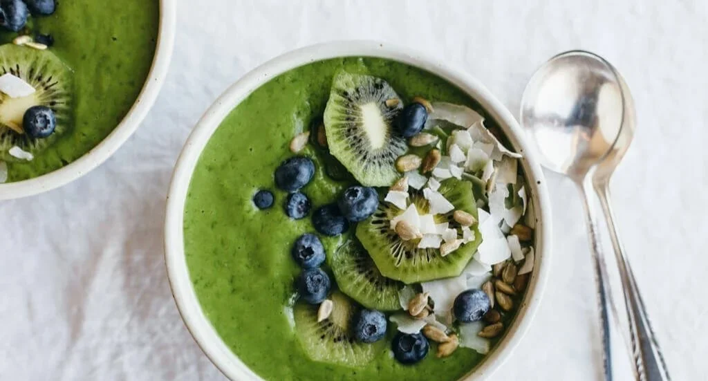 Sauberer grüner Smoothie-Bowl mit frischen Zutaten und buntem Topping