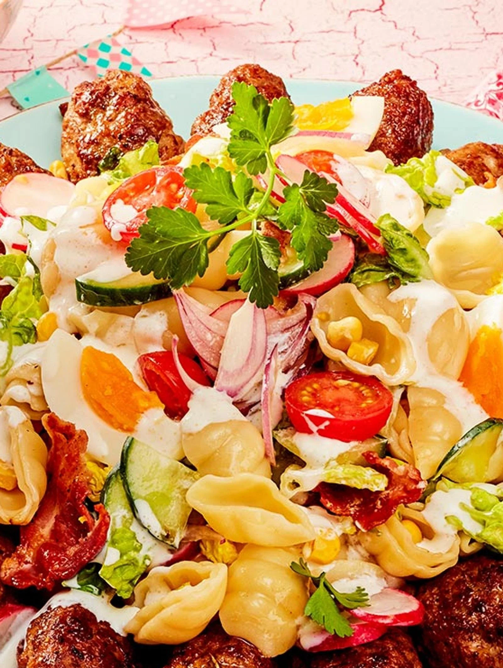 Tsatsiki-Nudelsalat mit Mini-Bifteki auf einem Teller serviert