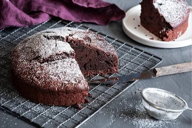 Veganer Schokoladenkuchen auf einem Holzbrett mit minimaler Dekoration