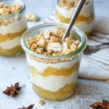 Apfel-Crumble mit Zimtcreme auf einem Teller serviert.