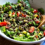 Beluga-Linsensalat mit gebratener Zucchini auf einem Teller