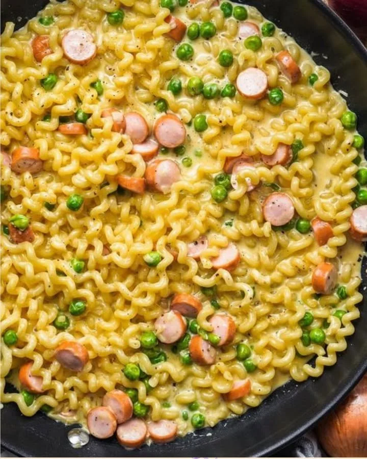 Cremige Nudelpfanne mit Wiener Würstchen und Schmelzkäse auf einem Teller.