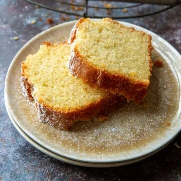 Saftiger Sandkuchen auf einem Teller, dekoriert mit Puderzucker.