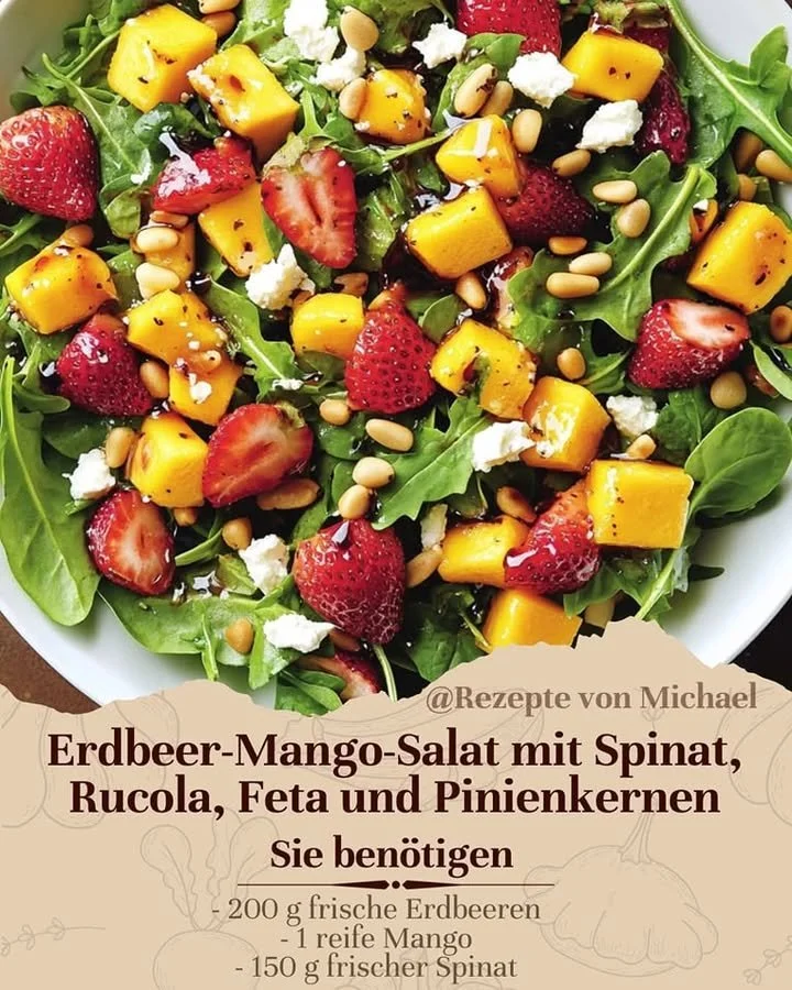 Erdbeer-Mango-Salat mit Spinat, Rucola, Feta und Pinienkernen auf einem Teller