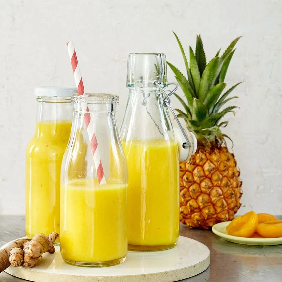 Ein Glas erfrischender Gelber Smoothie mit frischen Früchten und grünem Gemüse.