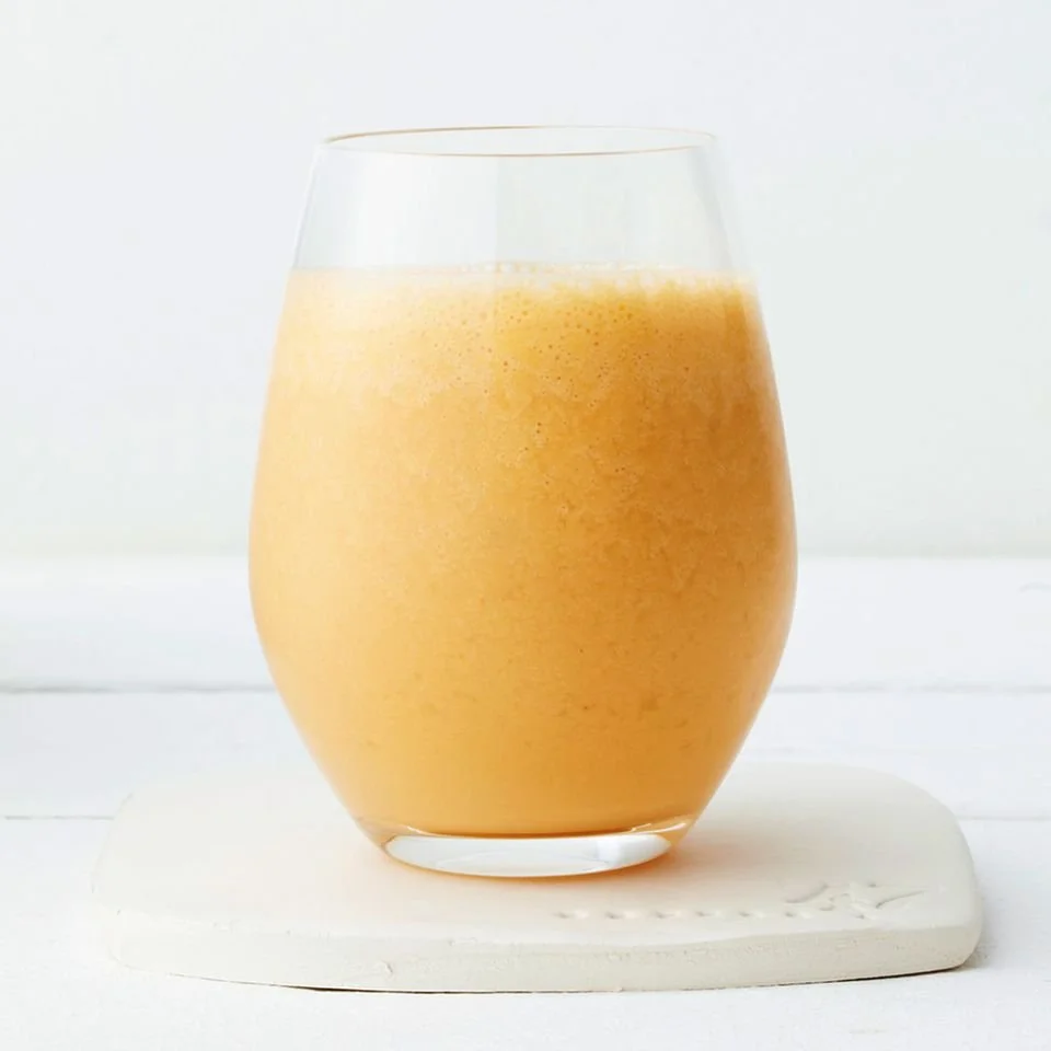 Karotten-Ingwer-Smoothie in einem Glas mit frischen Karotten und Ingwerwurzeln