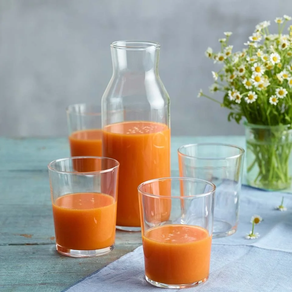 Mango-Karotten-Smoothie in einem Glas, verziert mit frischen Karotten und Mangostücken.