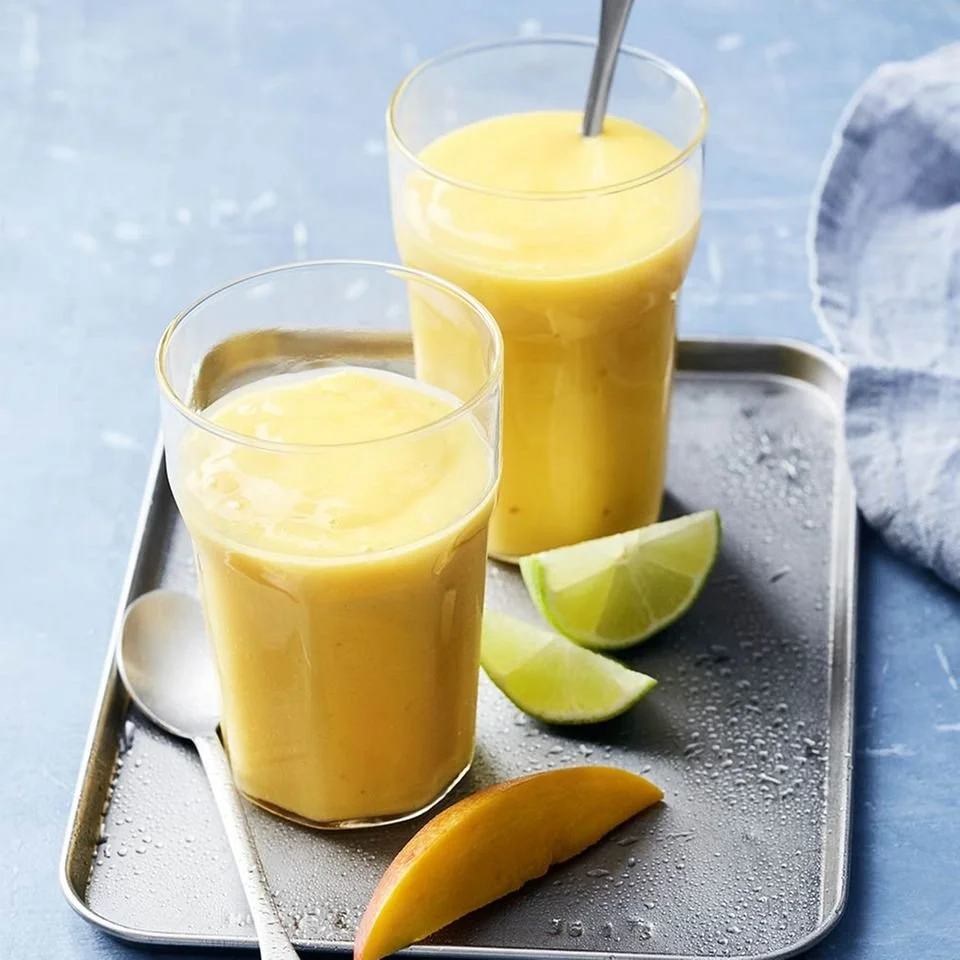 Erfrischender Mango-Smoothie in einem Glas mit frischen Mangostücken