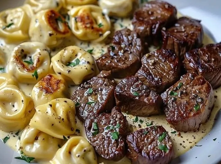 Leckeres Steak mit Knoblauchbutter und Tortellini auf einem Teller