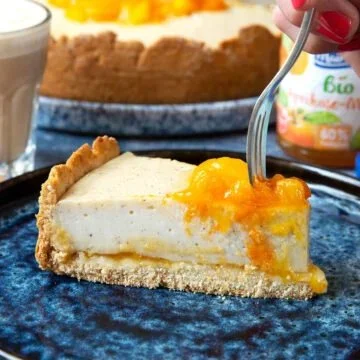 Veganer Käsekuchen mit Aprikose und Mango auf einem Teller.