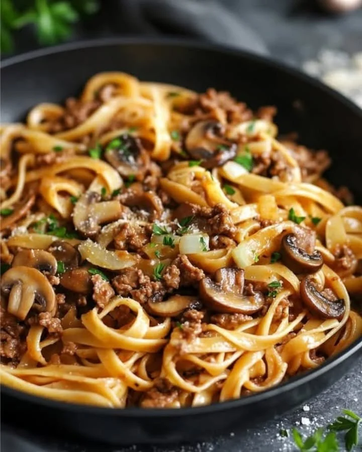 Bandnudeln mit Hackfleisch und Champignons in einem Teller serviert