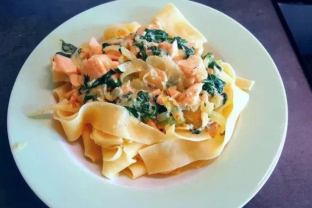 Tagliatelle mit frischem Spinat und geräuchertem Lachs auf einem Teller