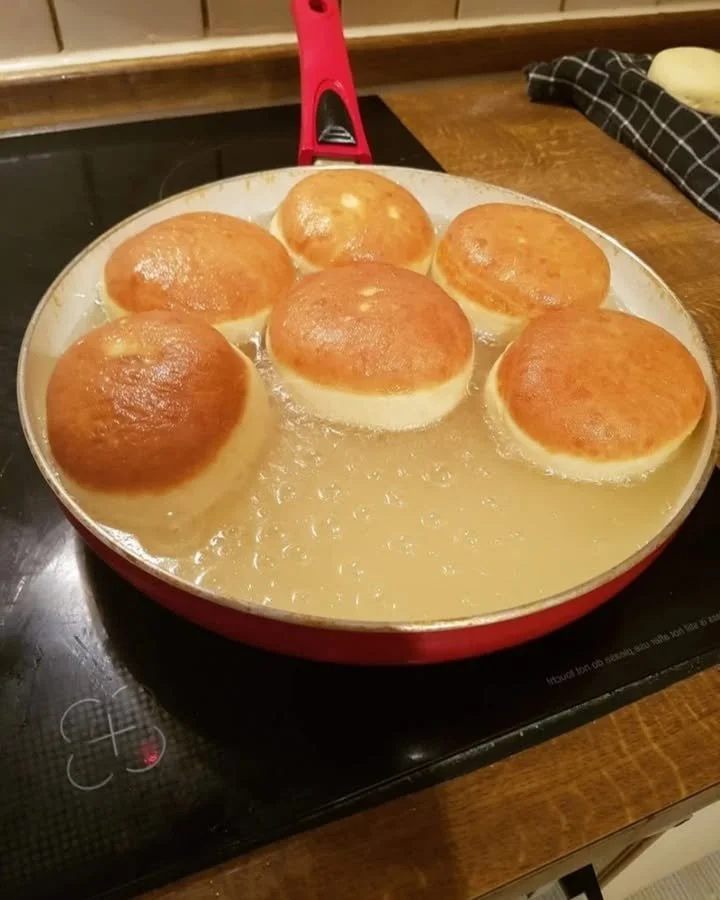 Ein Teller frischer Krapfen mit Puderzucker und Marmelade gefüllt