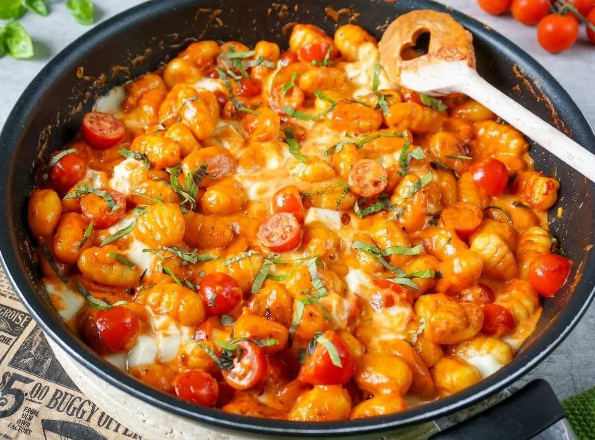 Gnocchi-Pfanne mit Tomaten und Mozzarella auf einem Teller serviert.