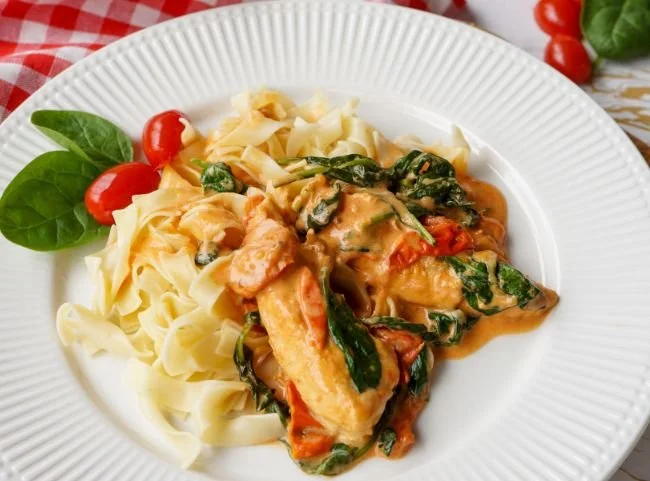 Hähnchenpfanne mit Spinat und Parmesan Soße auf einem Teller serviert