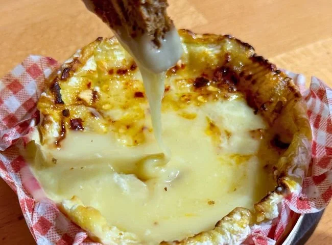 Hausgemachter Ofenkäse aus der Heißluftfritteuse serviert mit frischen Brotwürfeln.