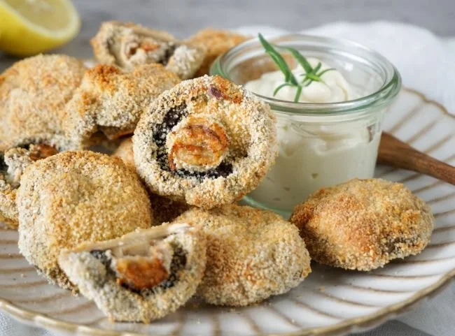 Panierte Champignons aus der Heißluftfritteuse serviert auf einem Teller