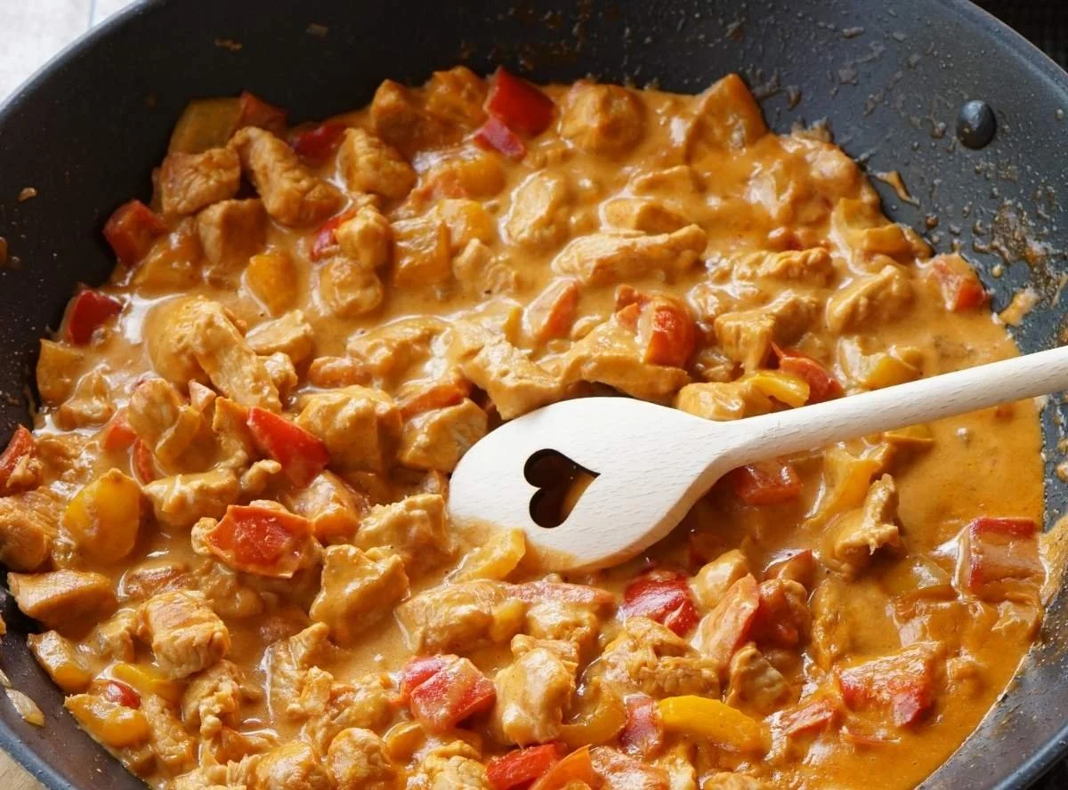 Delikates Paprika-Sahne-Hähnchen mit cremiger Sauce serviert auf einem Teller.