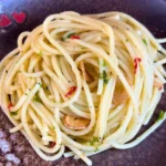 Teller mit Spaghetti aglio e olio und Peperoncino auf einem Holztisch